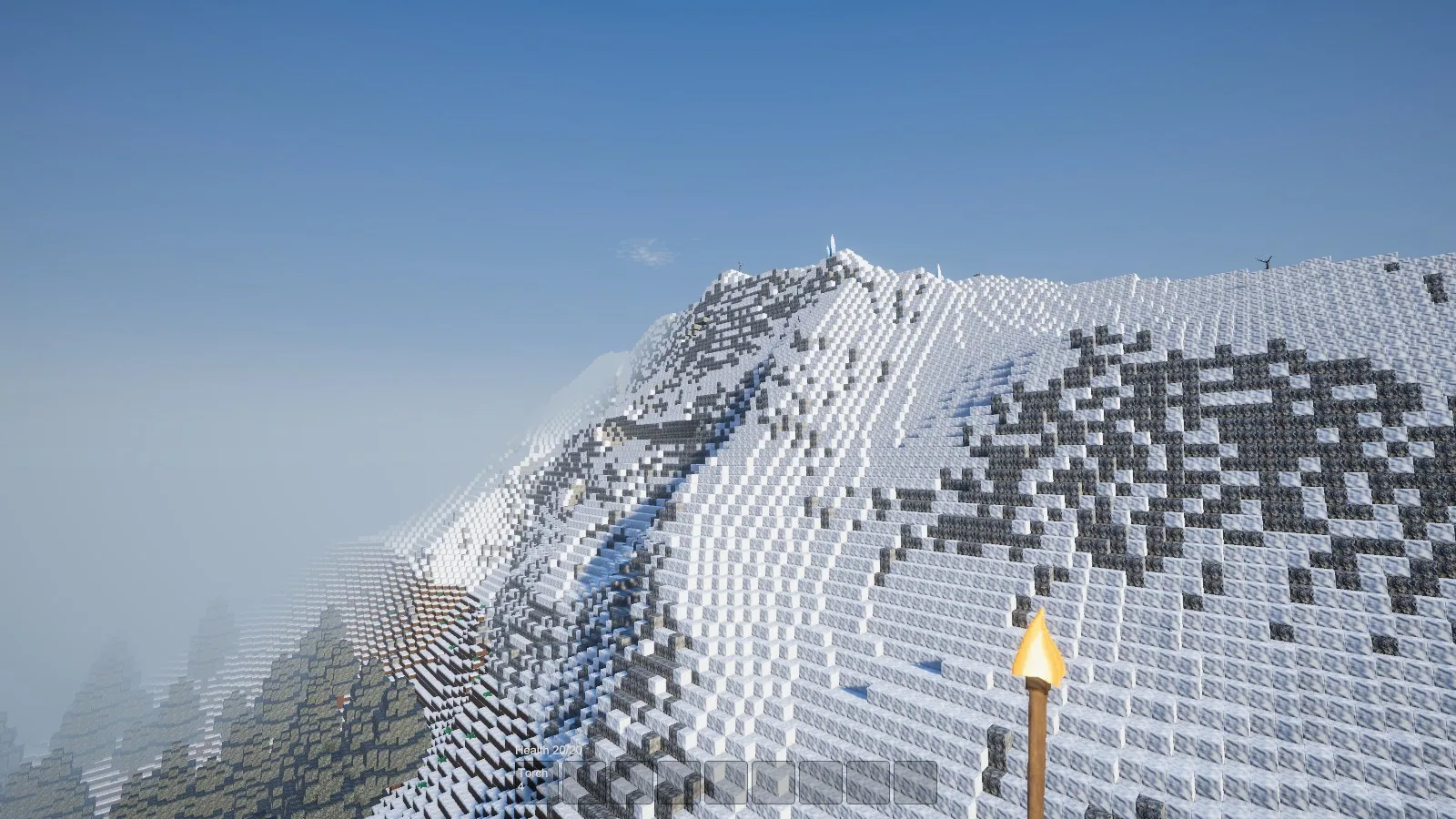 A massive snow-capped voxel mountain with exposed rock and spruce forest on the lower slopes.
